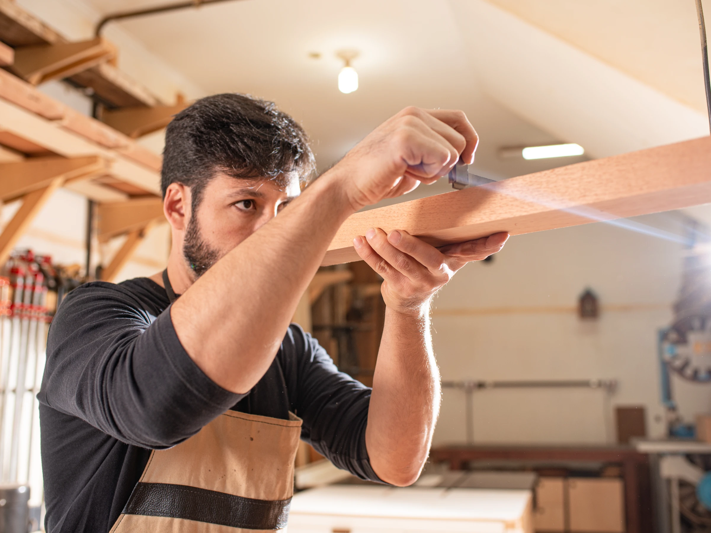 Rafael checking the alignment of a piece of wood in the workshop
